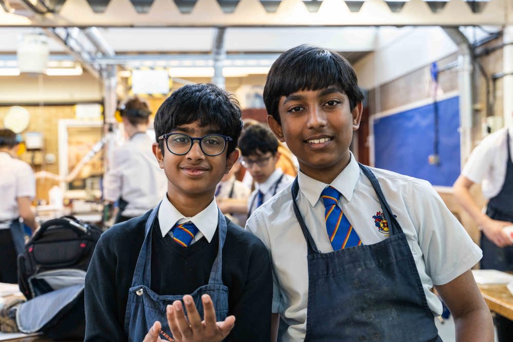 Two pupils looking into the camera and smiling in the DT workshop